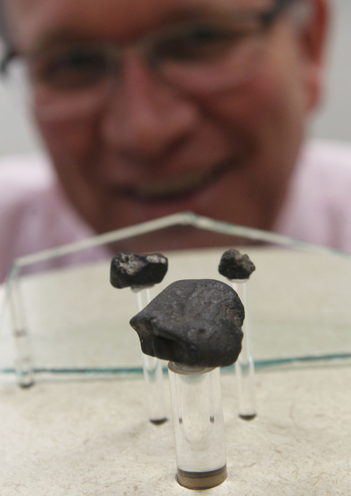 Al Hartmann  |  The Salt Lake Tribune
Seth Jarvis of the Clark Planetarium looks at three meteorites that fell over Russia in February 2013 to be on display. Along with the meteorites is a piece of glass that imploded and injured people from the event. A meteor is the flash of light we see in the sky, which is caused by a meteoroid. Any surviving pieces that land on Earth are then called meteorites.