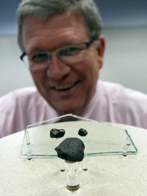 Al Hartmann  |  The Salt Lake Tribune
Seth Jarvis of the Clark Planetarium looks at three meteorites that fell over Russia in February 2013 to be on display. Along with the meteorites is  a piece of glass that imploded and injured people from the event. A meteor is the flash of light we see in the sky, which is caused by a meteoroid. Any surviving pieces that land on Earth are then called meteorites.