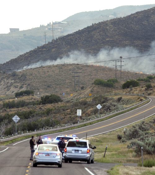 Steve Griffin | The Salt Lake Tribune

Utah Highway Patrol officers block the road heading to Rockport Reservoir as the Rockport 5 Fire burns in the background near Wanship Tuesday August 13, 2013.