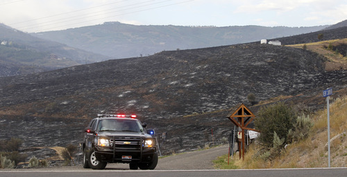 Al Hartmann  |  The Salt Lake Tribune
A Summit County Sheriff's officer blocks access road off SR 32 to the Rockport Estates subdivision just south of Rockport Reservoir Wednesday morning August 14. The mountainside burned from Tuesday's Rockport wildfire.