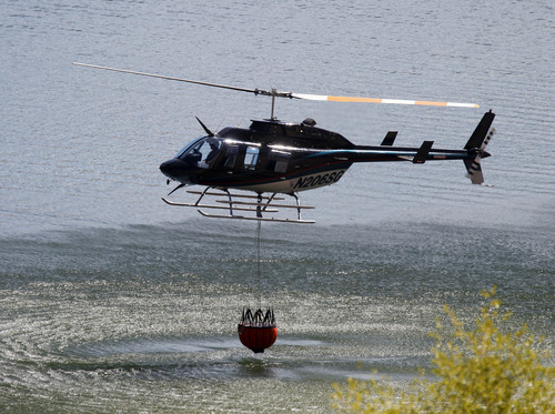 Al Hartmann  |  The Salt Lake Tribune
A helicopter with a water bucket dips into Rockport Reservoir to drop water on hot spots about 2 miles to the south on the Rockport Fire that started Tuesday and destroyed a dozen homes in the Rockport Estates. Helicopters flew hundreds of water drops Wednesday August 14 to fight the fire.