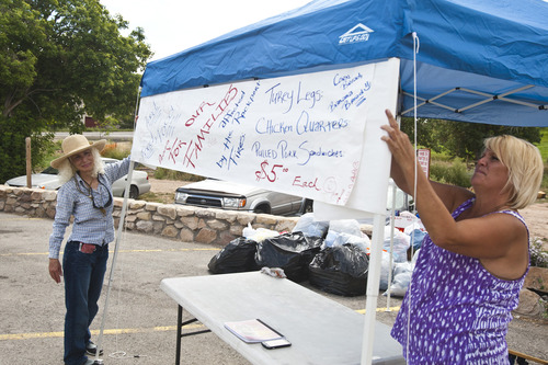 Chris Detrick  |  The Salt Lake Tribune
Sherri Berntsen, left, and Kim Alderman hang up a sign during a fundraiser for victims of the Rockport 5 Fire at Rafter B gas station Saturday August 17, 2013. They cooked 100 turkey legs, 100 chicken quarters and about 150 pulled pork sandwiches that were sold to raise money.