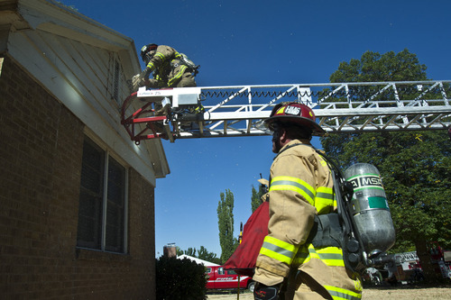 Chris Detrick  |  The Salt Lake Tribune
Salt Lake City Capt. Dan Gish watches as firefighter John McNeill cuts a ventilation hole in the gable during a training drill on an old home, which is scheduled to be demolished, in Salt Lake City Wednesday August 21, 2013.