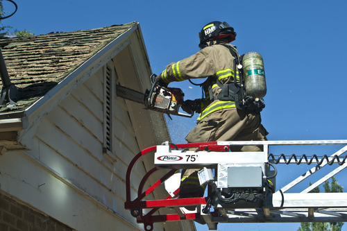 Chris Detrick  |  The Salt Lake Tribune
Salt Lake City firefighter John McNeill cuts a ventilation hole in the gable during a training drill on an old home, which is scheduled to be demolished, in Salt Lake City Wednesday August 21, 2013.