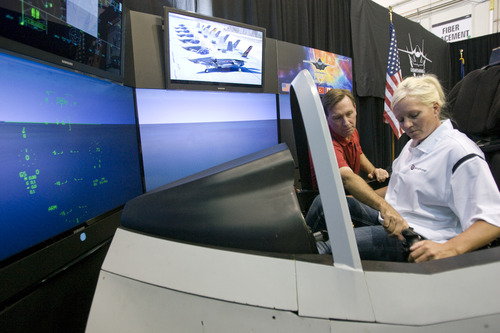 Rick Egan  | The Salt Lake Tribune 

Gary Hentz gives directions to ATK employee Charlene Yocham as she sits in the F-35 Lightning II interactive cockpit demonstrator at ATK on Wednesday, Aug. 20, 2013.  The cockpit demonstrator simulates the fighter aircraft's advanced technologies and combat capabilities.