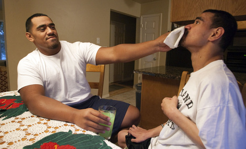 Steve Griffin | The Salt Lake Tribune

Bryan Mone, left, helps his brother, Filimone, eat his dinner at their home in Rose Park, Utah Aug. 20, 2013. Filimone is severely  handicapped and needs assistance to eat. Bryan, who is a top football recruit and plays football for Highland High School, has maintained a close relationship with his brother and family.