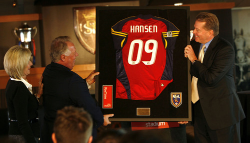 Photo by Leah Hogsten  |  The Salt Lake Tribune
Above, Real Salt Lake pro soccer team Chairman DaveChecketts (right) presents Del Loy Hansen with his own Real jersey. At left is Hansen's wife Lynnette Hansen. 
Real Salt Lake pro soccer team Chairman Dave Checketts announced Wednesday that Utah entrepreneur and real estate developer Dell Loy Hansen has purchased a co-ownership in SCP Worldwide's Utah sports properties. Hansen will serve as Vice Chairman and Alternate Governor for REal Salt Lake.