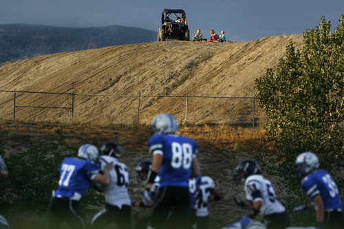 Scott Sommerdorf   |  The Salt Lake Tribune
Duchesne and Carbon play as a family watches from a hilltop near the Carbon High football field. The Eagles would go on to an easy 35-0 win against Carbon High which ran their winning streak to 37 games, setting the Utah state record for consecutive wins, Friday, September 6, 2013.