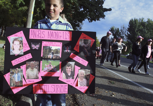 Keith Johnson | The Salt Lake Tribune
 
Arrington Purvis, 7, holds a sign dedicated to the memory of friends and loved ones who have passed away due to cancer as people participating in the Making Strides Against Breast Cancer walk past  in Salt Lake City, October 12, 2013.