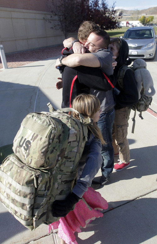 Al Hartmann  |  The Salt Lake Tribune
Sgt. 1st Class Jason Lyday hugs his children as his daughter Rachel carries his pack to a wating bus at Camp Williams. They are from Eagle Mountain. He is among 13 members of the Utah National Guard 115th Engineer Facilities Detachment that left Camp Williams Tuesday October 15 for deployment to Afghanistan for one year.