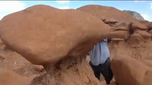 A screen grab from a video showing men knocking over one of the formations at Goblin Valley State Park.