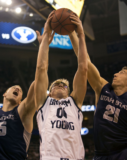Lennie Mahler  |  The Salt Lake Tribune
BYU's Erik Mika pulls in a rebound over Utah State's Jordan Stone and Spencer Butterfield in the second half of their game at EnergySolutions Arena in Salt Lake City, Saturday, Nov. 30, 2013.