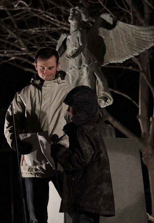 Leah Hogsten  |  The Salt Lake Tribune
Hunter Gillman, joined by his father Luke Gillman, reads a long poem in honor of his brother Carson Gillman who died in infancy.  Friends and family whose infants and young children have died, gathered at the Christmas Box Angel statue in the Salt Lake City Cemetery for a candlelight vigil in remembrance, December 6, 2013.