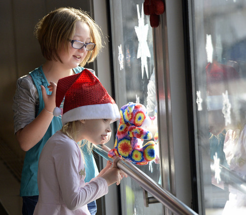 Al Hartmann  |  The Salt Lake Tribune
Moira LeGrand, 9, left, and friend Danika Blamires, 7, watch from the concourse window for the "Polar Express" plane to arrive at the Salt Lake airport Thursday Dec. 12, 2013. The two girls both lost their fathers in the Iraq war. They were among 20 children and parents from military families who lost a parent in the recent wars in Iraq and Afghanistan to fly to Dallas for a one-week vacation on the "Snowball Express" courtesy of  American Airlines.