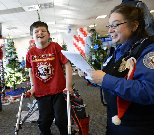 Al Hartmann  |  The Salt Lake Tribune
TSA agent Jennifer Griggs talks to Cayson Simmons at the Salt Lake airport Thursday Dec. 12, 2013. He lost his father five years ago. He was among 20 children and parents from military families who lost loved one in the recent wars in Iraq and Afghanistan to fly to Dallas for a one-week vacation on the "Snowball Express" courtesy of  American Airlines