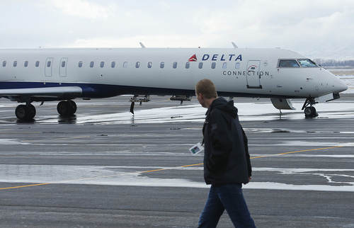A Provo airport official walks past a Delta plane at the Provo Airport on December 19, 2013 in Provo, Utah. Several Delta flight were diverted and landed at the Provo Airport after the Salt Lake City a Airport was closed standing several hundred passengers.  (Photo by George Frey  |  Special to the Tribune)