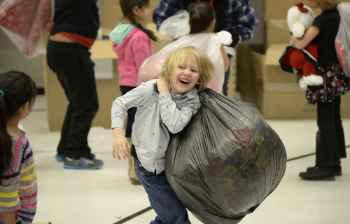 Francisco Kjolseth  |  The Salt Lake Tribune
Lucian Perry, 6, is overjoyed by the heavy load as hundreds of generous residents from five Utah counties along with volunteers from HeritageWest and SouthWest Credit Unions treat 550 students from Lincoln Elementary School in Salt Lake City to a "need" and "want" requests for Christmas on Thursday, Dec. 19, 2013. The Title One school, where 96% of the kids live under the poverty line and nineteen foreign languages are spoken was filled with big smiles and excitement as volunteers handed out bags of gifts.
