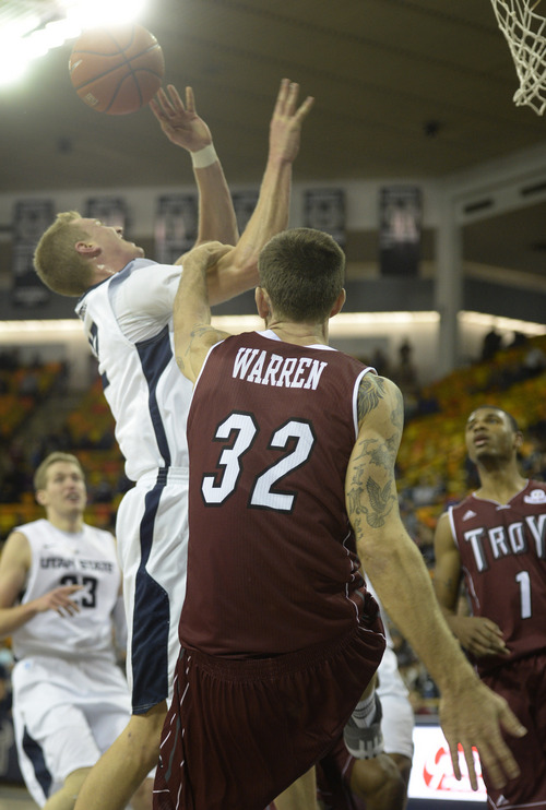 Rick Egan  | The Salt Lake Tribune 

Utah State Aggies guard/forward Danny Berger (12) is fouled by Troy Trojans center Josh Warren (32), in basketball action, Utah State vs.Troy, in the final game of the Basketball Travelers Classic Tournament, at the Dee Glen Smith Spectrum, in Logan, Friday, December 20, 2013.