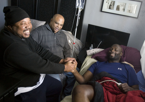 Keith Johnson | The Salt Lake Tribune

Bronzell Miller, right, receives a visit from friends Rick Sealey, left, and Jerome Marshall at home in West Jordan, Utah, December 9, 2013. Miller, a University of Utah defensive end from 1993-94, and who played a year in the NFL, has multiple myeloma and was told by doctors that he has only 2-4 weeks to live. He currently receives hospice care from his partner Marnie Oliver who is trying to raise money to cover Miller's end-of-life and funeral expenses. Miller doesn't have life insurance and he has 9 children.