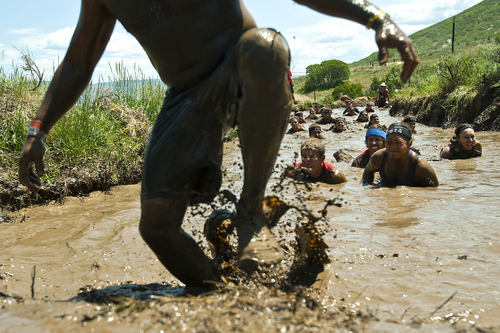 Chris Detrick  |  The Salt Lake Tribune
Erica Jessop, 36, right, of Sandy, Utah, crawls through a mud pit during the Utah Spartan Beast Race at Soldier Hollow Saturday June 29, 2013. The 12-mile race included obstacles like mud pits with barbed wire, rope climbs, jumping over fire and climbing an eight-foot wall. Jessop finished with a time of 4:15:31.