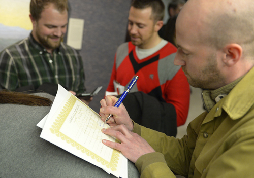 Keith Johnson | The Salt Lake Tribune

Officiant Derek Snarr signs the marriage certificate of Jason Dautel, left and Micah Unice after they were married outside the Salt Lake County clerks office, Friday, December 20, 2013. A federal judge in Utah Friday struck down the state's ban on same-sex marriage, saying the law violates the U.S. Constitution's guarantees of equal protection and due process.