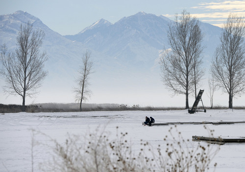 Al Hartmann |  The Salt Lake Tribune 
Two fishermen sit at the end of a dock at Utah Lake State Park Friday January 3 to fish a hole in the ice on the mostly frozen lake.