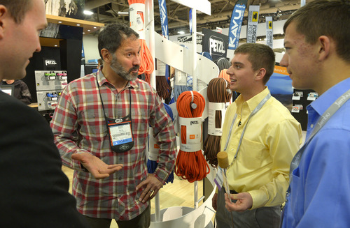 Rick Egan  | The Salt Lake Tribune 

 Salt Lake County Mayor Ben McAdams, (left) talks to Nazz Kurth, Petzl, about the  Wolf em Stick, made by Tanner and Spencer Harrison (right), as they tour the Outdoor Retailers Convention, along with at the Salt Palace, Thursday, January 23, 2014.