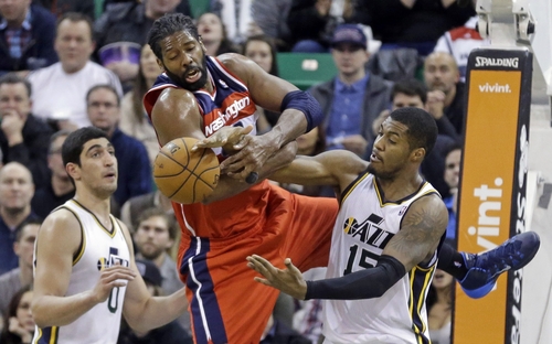 Utah Jazz's Derrick Favors, left, and Washington Wizards' Nene, center, struggle for the ball as Jazz's Enes Kanter (0) watches during the fourth quarter of an NBA basketball game Saturday, Jan. 25, 2014, in Salt Lake City. The Jazz won 104-101. (AP Photo/Rick Bowmer)