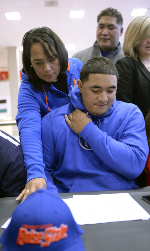 Al Hartmann  |  The Salt Lake Tribune 
East High School's Tennessee Su'eSu'e, looks over papers with his mother Sina and father Helaman before signing a letter of intent to play for Boise State in a signing ceremony at East High School Wednesday morning February 5, 2014. He overcame a heart condition to become a D-I football recruit.
