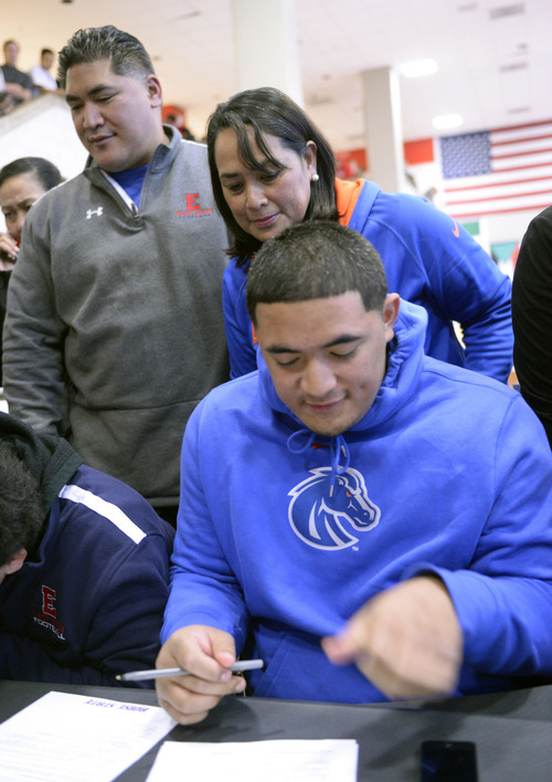 Al Hartmann  |  The Salt Lake Tribune 
East High School's Tennessee Su'eSu'e, looks over papers with his mother Sina and father Helaman before signing a letter of intent to play for Boise State in a signing ceremony at East High School Wednesday morning February 5,  2014. He overcame a heart condition to become a D-I football recruit.