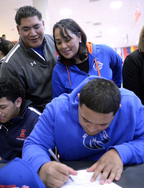 Al Hartmann  |  The Salt Lake Tribune 
East High School's Tennessee Su'eSu'e, signs papers to play for Boise State as his parents Sina and Helaman look on in a signing ceremony at East High School Wednesday morning February 5, 2014. He overcame a heart condition to become a D-I football recruit.