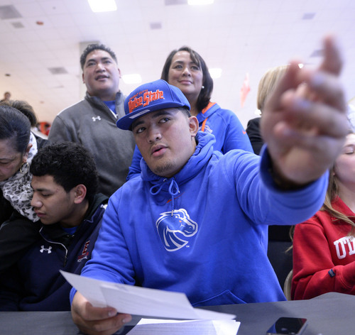 Al Hartmann  |  The Salt Lake Tribune 
East High School's Tennessee Su'eSu'e, passes over his letter of intent to play football at Boise State as his parents Sina and Heleman watch in a signing ceremony at East High School Wednesday morning February 5, 2014. He overcame a heart condition to become a D-I football recruit.