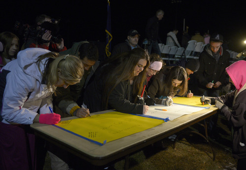 Rick Egan  | The Salt Lake Tribune 

Supporters sign posters at the candlelight vigil in honor of Sgt. Cory Wride and injured Deputy Greg Sherwood, in Spanish Fork, Sunday, February 2, 2014.  Johnny Revill , family spokesman is on the right.