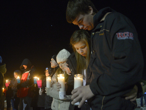 Rick Egan  | The Salt Lake Tribune 

Supporters bow their heads in prayer at the candlelight vigil in honor of Sgt. Cory Wride and injured Deputy Greg Sherwood, in Spanish Fork, Sunday, February 2, 2014.  Johnny Revill , family spokesman is on the right.
