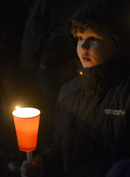 Rick Egan  | The Salt Lake Tribune 

Michael,9, holds a candle at the candlelight vigil in honor of Sgt. Cory Wride and injured Deputy Greg Sherwood, in Spanish Fork, Sunday, February 2, 2014.  Johnny Revill , family spokesman is on the right.