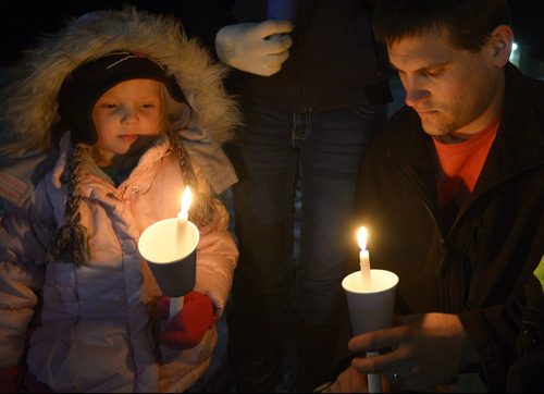 Rick Egan  | The Salt Lake Tribune 

Hayden Mitchell, 3, and her dad Danny Mitchell, hold candles at the candlelight vigil in honor of Sgt. Cory Wride and injured Deputy Greg Sherwood, in Spanish Fork, Sunday, February 2, 2014.  Johnny Revill , family spokesman is on the right.