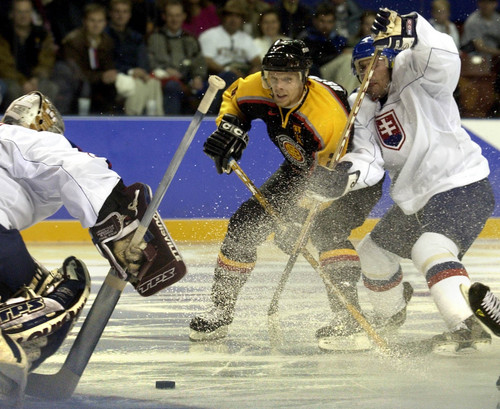 |  Tribune file photo
Germany's Stefan Ustorf (21) attempts to skate past b Slovokia's Miroslav Satan (18) and goalkeeper Pavol Rybar, February 9, 2002 during the Winter Olympics in Salt Lake City. Germany went on to win 3-0.