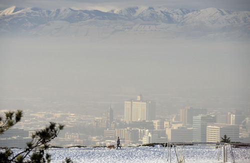 Al Hartmann  |  The Salt Lake Tribune
A woman walks her dog along the track at 11th Avenue Park just above the polluted air buiding up in dowtntown Salt Lake City Monday morning December 30.  The Utah Division of Air Quality rated the air in the orange range with a health advisory for elderly and persons with existing heart or lung disease to stay indoors and reduce physical activity.