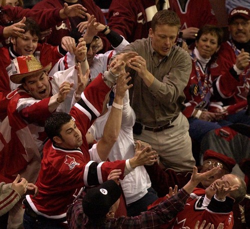 Trent Nelson  |  Tribune file photo
Canadian fans scramble for a flying hockey puck during the third period of the Czech Republic vs. Canada men's hockey during the 2002 Winter Olympics.