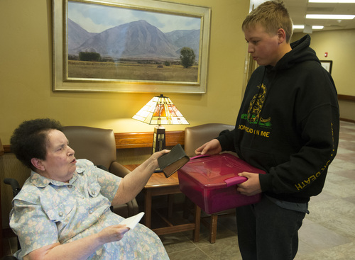 Rick Egan  | The Salt Lake Tribune 

Wyatt Scott, 15, hands Kathleen Warren a box containing old photos and news clippings of her late husband, Chuck Warren, at a care center in Payson, Sunday, February 16, 2014. Chuck Warren was shot while on duty for the Utah Highway Patrol in 1969.