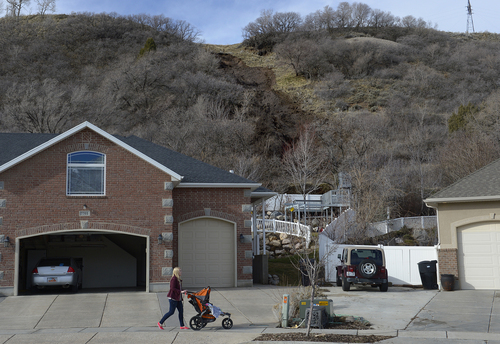 Scott Sommerdorf   |  The Salt Lake Tribune
A woman on a stroll below a mudslide on a hill behind homes on 1650 East in South Weber City. The slide occurred after the hillside was weakened by overnight rains, seen Friday, Feb. 28, 2014. No homes below were damaged, but might be threatened by further rain. The same area was hit with a landslide in 2007 neighbors said.