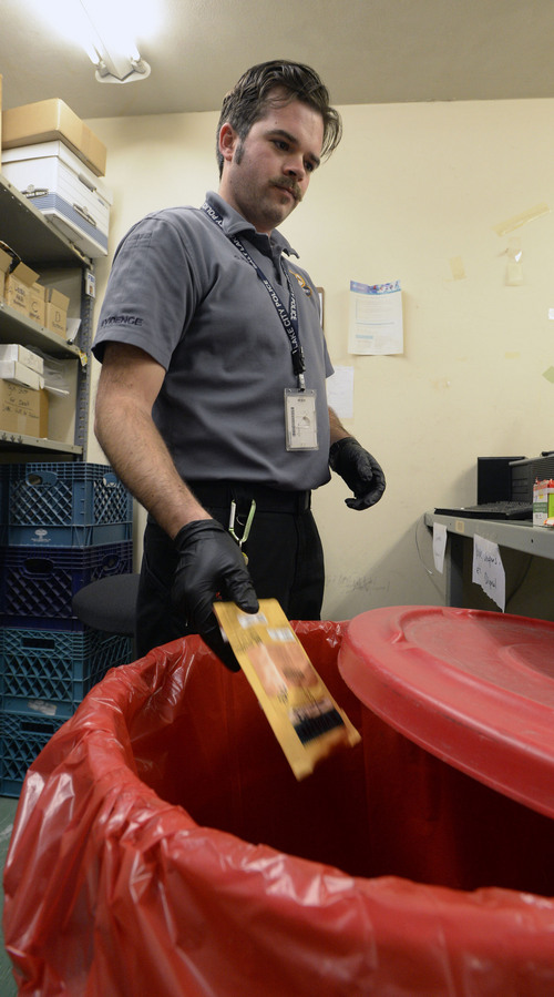 Al Hartmann  |  The Salt Lake Tribune 
Evidence technician Cody Nixon, throws biohazard evidence into barrel with safety liner at the Salt Lake Police Department evidence room Friday February 28.  Items of urine, blood draws from DUI tests, used syringes, DNA swabs and bloody clothing no longer used for court evidence is scanned and disposed of in the bio waste barrels.  Stericycle picks up the contents and takes it to their waste disposal facility.