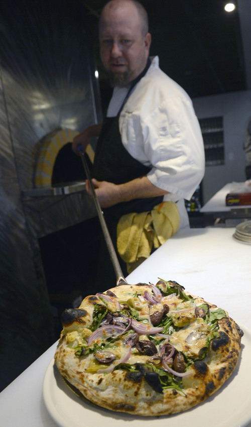Al Hartmann  |  The Salt Lake Tribune 
Chef Michael Jewell pulls a Spinach and Roasted Artichoke Pizza with black olive, tallegio, house ricotta and red onion from the oven at Bistro 222.