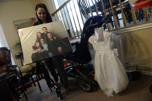 Francisco Kjolseth  |  The Salt Lake Tribune
Catrina Nelson of West Jordan holds a recently made family portrait that was donated to her in honor of her youngest daughter Charlee, 6, who suffers from Late Infant Batten Disease, a terminal inherited disorder of the nervous system that leads to seizures and loss of vision and motor skills. At right is the dress they plan to bury her in when the time comes, which is expected to be soon.