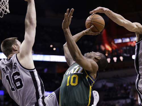 Utah Jazz's Alec Burks (10) is blocked from behind by San Antonio Spurs' Manu Ginobili, right, of Argentina, as Aron Baynes assists on the play during the first half of an NBA basketball game, Sunday, March 16, 2014, in San Antonio. (AP Photo/Eric Gay)