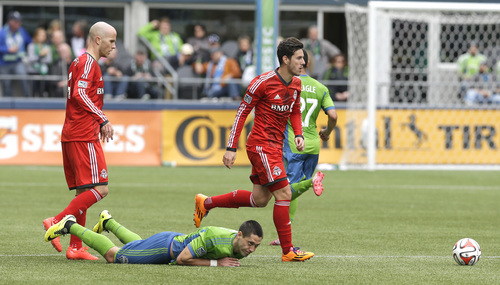 Seattle Sounders's Clint Dempsey, second from left, goes down after battling with Toronto FC's Michael Bradley, left, and Alvaro Rey, right, for the ball in the first half of an MLS soccer match on Saturday, March 15, 2014, in Seattle. (AP Photo/Ted S. Warren)