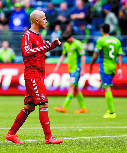 Toronto FC midfielder Michael Bradley, left, celebrates after Toronto beat the Seattle Sounders 2-1 in the first half of a MLS soccer match, Saturday, March 15, 2014, in Seattle. Sounders' Clint Dempsey (2), who is Bradley's teammate on the U.S. men's national team, is in the background at right. (AP Photo/Ted S. Warren)