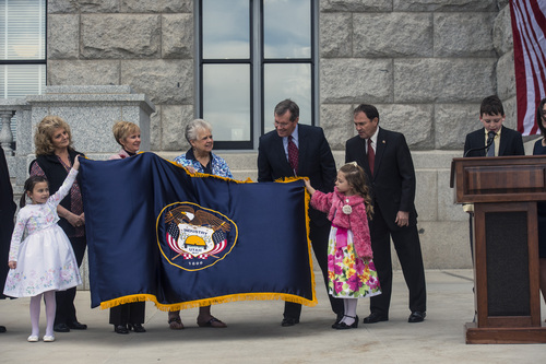 Chris Detrick  |  The Salt Lake Tribune
Sophia Molenaar, 6, and Arianna Vasquez, 6, hold a newly embroidered Utah State flag as Michael Molenaar, 10, speaks during a ceremony marking the 100th anniversary of the laying of the cornerstone of the Utah State Capitol Friday, April 4, 2014. Former Gov. Mike Leavitt and Gov. Gary Herbert are in the back, right.