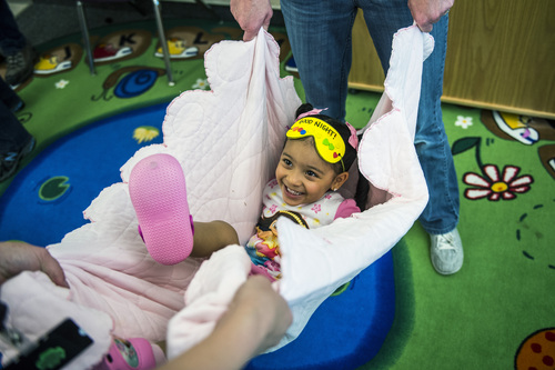 Chris Detrick  |  The Salt Lake Tribune
Sofia Varas, 2, swings in a blanket during 'Literacy Night' at Kauri Sue Hamilton School Child Development Center Tuesday April 29, 2014. Families of special needs children who are part of the Early Intervention Program, age birth to 3-years-old, received a copy of the 'Napping House' by Audrey Wood and participated in activities throughout the evening  highlighted parts of the book.