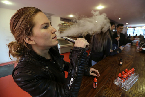 FILE - In this Feb. 20, 2014 photo, Talia Eisenberg, co-founder of the Henley Vaporium, uses her vaping device in New York. Under a New York City law taking effect Tuesday, April 29, 2014, vaporizing devices will be treated the same as a tobacco-based cigarette. The New York ban, along with similar measures in Chicago and Los Angeles and federal regulations proposed last week, are again igniting debate among public health officials, the e-cigarette industry and users lon the future of the popular devices.  (AP Photo/Frank Franklin II, File)